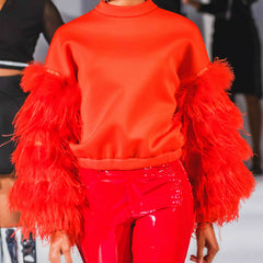 mode in a bright red top with feather sleeve on the runway, high fashion couture