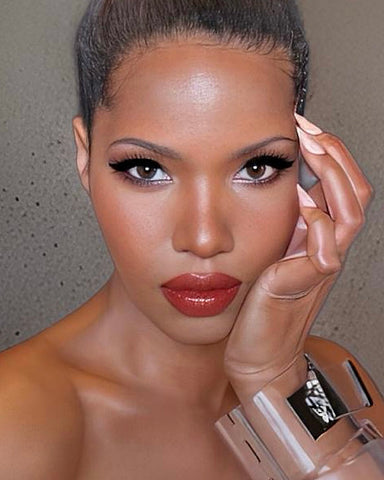 A person with smooth skin, makeup, and styled hair poses gracefully with a hand by their face, wearing the shiny Drop Lock Silver Lucite Bangle Bracelet by Nik Spruill.