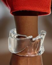 A translucent Tear Drop Lucite bracelet by Nik Spruill is worn on a wrist with a red sleeve.