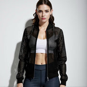 Woman wearing a black studded jacket over a white top and dark pants on a light gray background
