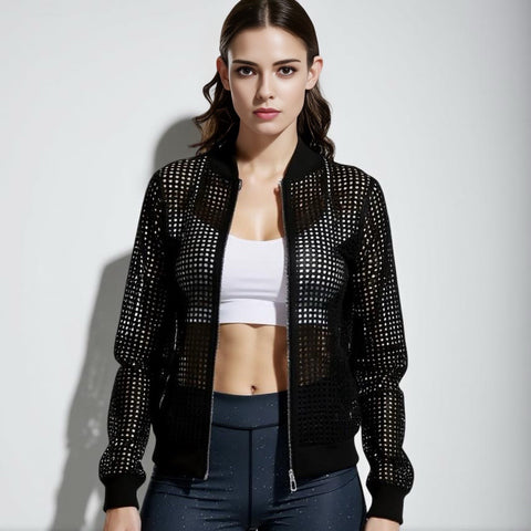Woman wearing a black studded jacket over a white top and dark pants on a light gray background