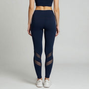 Navy blue leggings with mesh panels worn by a person on a light gray background