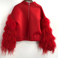 A Nik Spruill AIR SPACE RED TOP with a half-zip and feathered sleeves hangs elegantly on a hanger.