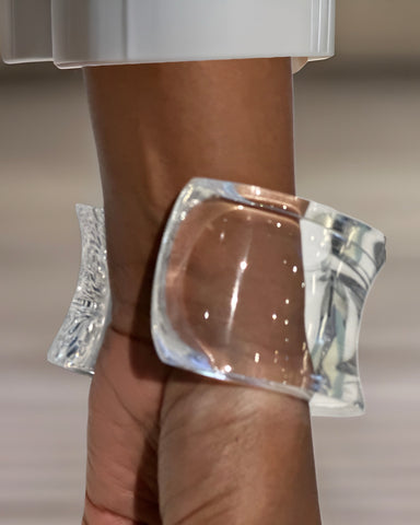 Close-up of a person's wrist adorned with the Dream Rain Lucite Cuff Bracelet by Nik Spruill. The background is blurred, highlighting the bracelet's timeless design and sophistication.