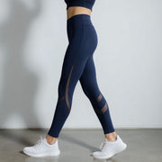 Person wearing navy blue leggings with mesh panels on a plain background