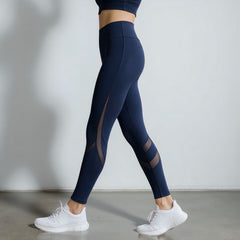 Person wearing navy blue leggings with mesh panels on a plain background