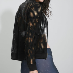 Person wearing a black mesh jacket and blue leggings on a plain background