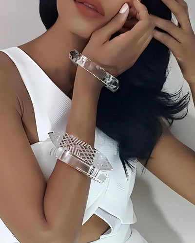 A woman wearing a white sleeveless top showcases two Nik Spruill Frost Lucite Bangle Bracelets with distinctive etched detailing on her wrist.