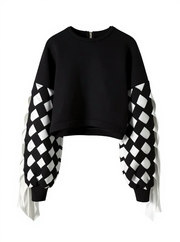 The Stitch Crochet Fringed Top by Nik Spruill is a striking black sweatshirt with unique ribbon interlock white and black sleeves. The ribbon hangs like fringe creating a unique look. Front view