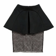 A Nik Spruill Black peplum top with sheer mesh overlay on a white background