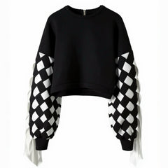 The Stitch Crochet Fringed Top by Nik Spruill is a striking black sweatshirt with unique ribbon interlock white and black sleeves. The ribbon hangs like fringe creating a unique look. Front view