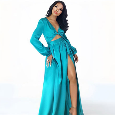 Woman wearing a turquoise dress with a deep neckline and high slit on a white background