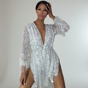 Woman wearing a silver fringe sequin dress against a plain background