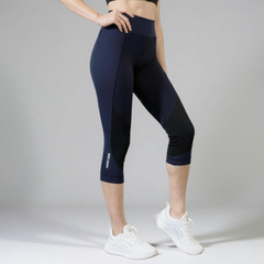Person wearing navy blue athletic leggings and white sneakers on a gray background