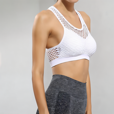White sports bra with mesh design worn by a person on a gray background