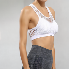 White sports bra with mesh design worn by a person on a gray background