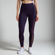 Person wearing dark purple leggings with mesh panels on a plain background