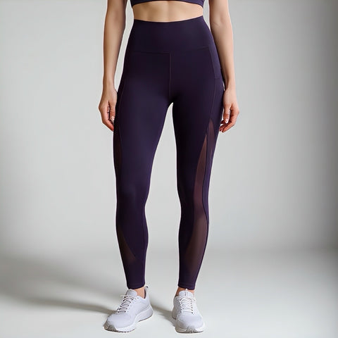 Person wearing dark purple leggings with mesh panels on a plain background