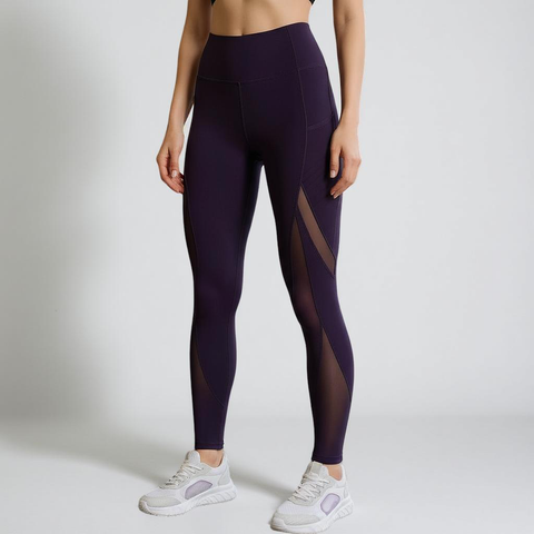 Person wearing dark purple leggings with mesh panels on a light gray background