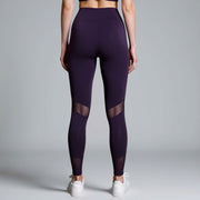 Purple leggings with mesh panels worn by a person on a gray background