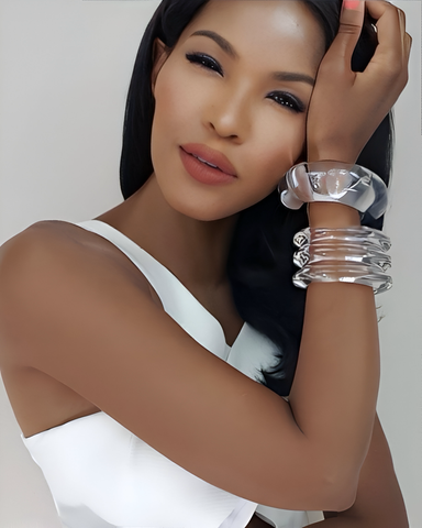 A woman with long black hair poses, wearing a sleeveless white outfit and multiple ARCTIC Clear Lucite cuff bracelets by Nik Spruill on her wrist.