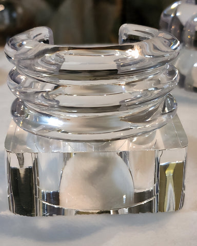 An exquisite ICEBERG sculpture by Nik Spruill features a clear, reflective glass with a layered, circular design. It sits elegantly on a polished base, reminiscent of a finely crafted Lucite bangle.