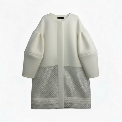 An oversized COCOON EMBRACE COAT by Nik Spruill, featuring puffed sleeves and a mesh lower section, hangs on a wooden hanger against a white background.