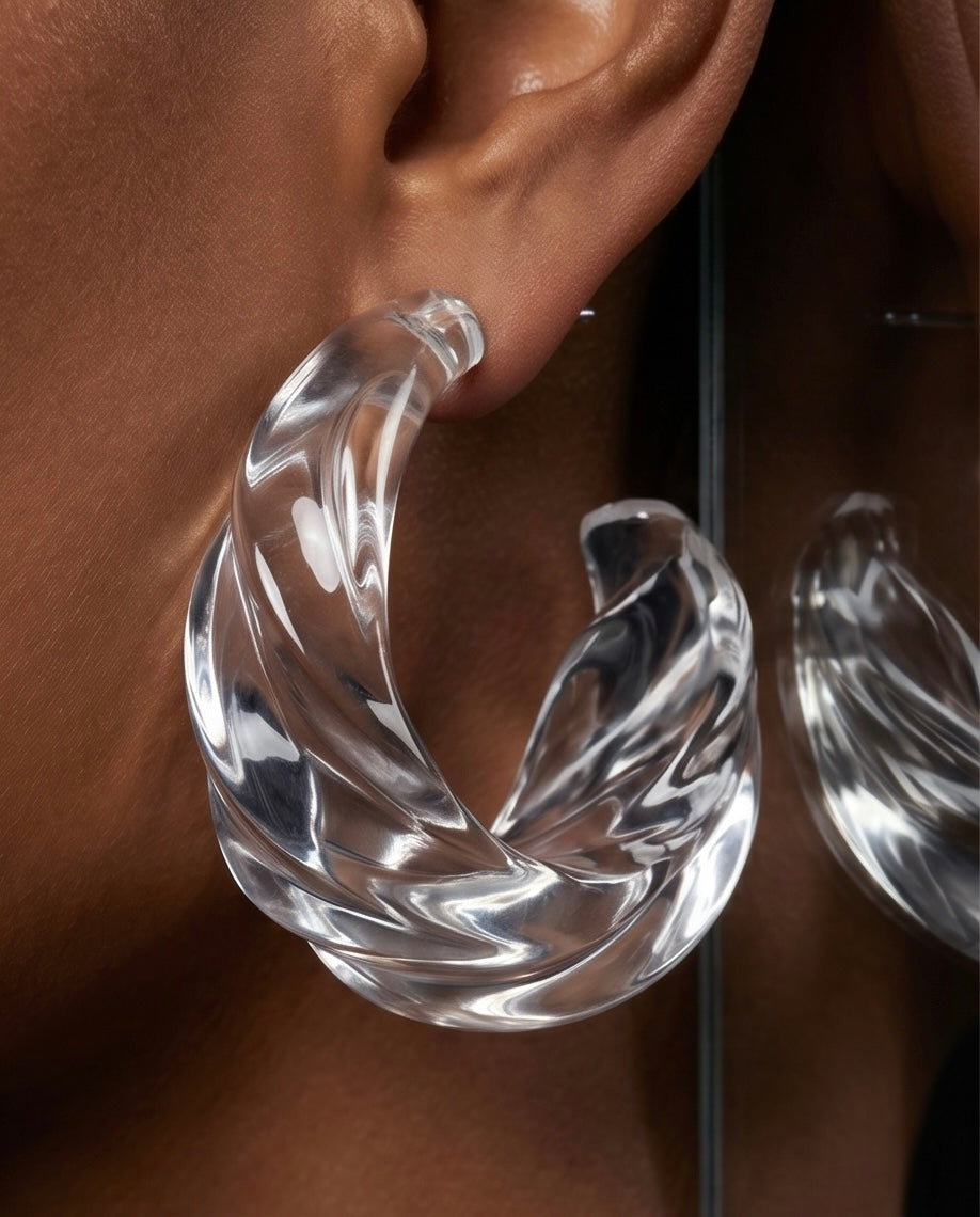 Close-up of clear lucite wave earrings worn on ear, sculptural transparent hoop earrings luxury styling