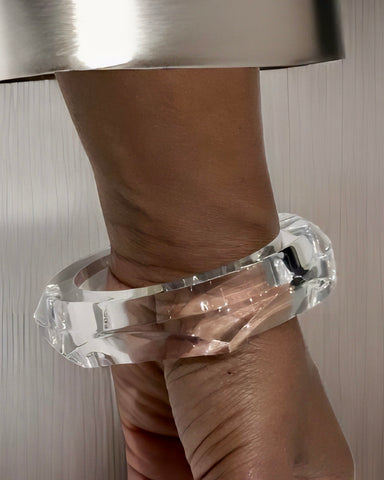 A close-up shot of a person’s wrist adorned with a thick Nik Spruill Hive Stackable Lucite Bangle Bracelet, set against a plain background.