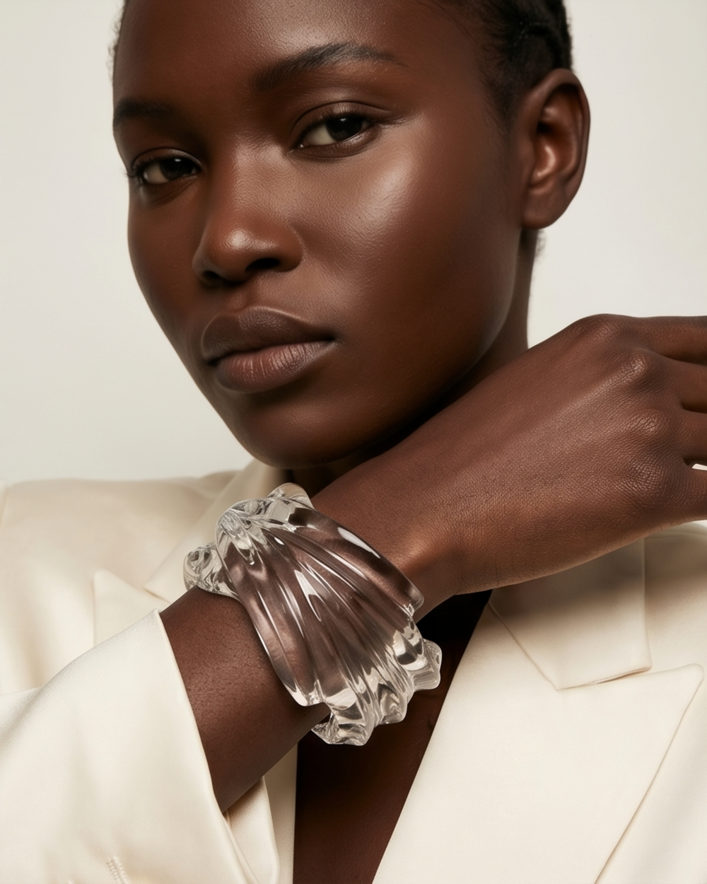Clear lucite cuff bracelet styled with cream blazer sleeve showing sculptural curved design