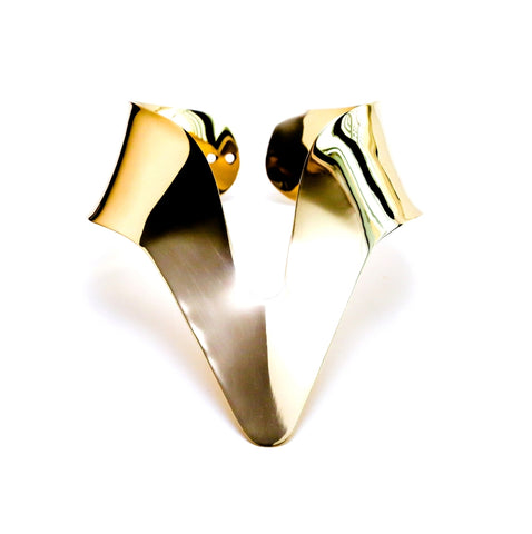 A close up of two Nik Spruill NANISCA GOLD metal objects on a white surface.
