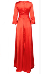A woman in a Nik Spruill Effortless Double Slit Maxi Dress - Orange is standing next to a white background.