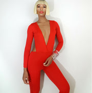 A woman is posing in a Nik Spruill Jade cutout backless jumpsuit - red.