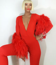 A woman in a Nik Spruill Jade cutout backless jumpsuit - red posing for a photo.