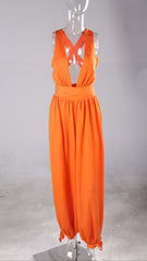 A Nik Spruill fearless one deep plunge backless jumpsuit - orange on a mannequin on a white background.