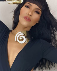 A woman wearing a black dress and a Nik Spruill AMENZA gold necklace.