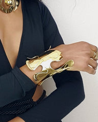 A woman wearing an OSHUN black dress and Nik Spruill gold jewelry.