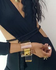 A woman wearing a black dress and a Nik Spruill DROP - GOLD bracelet.