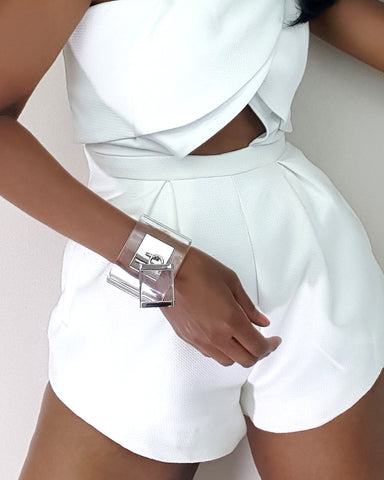 a woman in a white romper posing against a wall wearing Nik Spruill's DROP - SILVER.