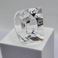 A clear IMAK ring sitting on top of a white Nik Spruill block.