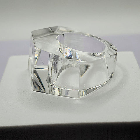 A clear ZENUS ring sitting on top of a white Nik Spruill box.