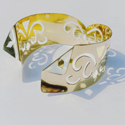 A Nzinga gold cuff bracelet with a design on it by Nik Spruill.