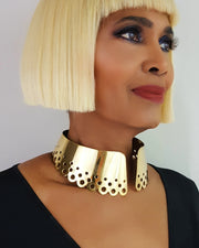A woman with blonde hair wearing a Nik Spruill DAHOMEY gold brass choker.