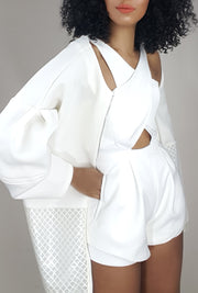 model side view in a white sleeveless romper with red lipstick in a bell sleeve white neoprene coat