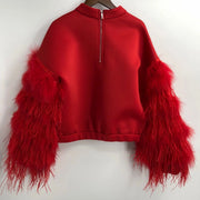 An Air Space Red Top by Nik Spruill with red feathers hanging on a hanger.