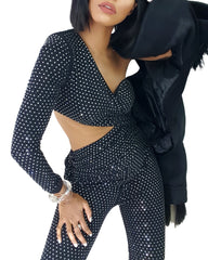 A woman wearing a Nik Spruill Spotlight One Shoulder Jumpsuit in black posing for a picture.