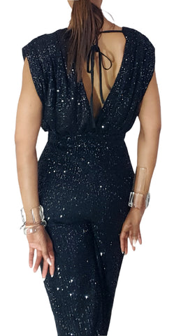 A woman wearing a Nik Spruill Glitz Sequined Jumpsuit in black and a hat.