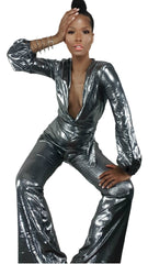 A woman is posing in a Nik Spruill DASS silver metallic jumpsuit.
