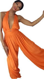 A woman in a Nik Spruill "The fearless one deep plunge backless jumpsuit - orange" posing for a picture.