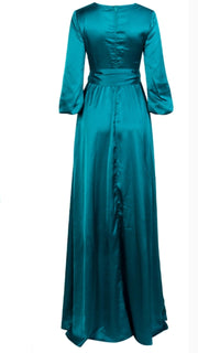 A woman in a long green dress becomes a woman in the Nik Spruill Limitless Double Slit Maxi Dress - Blue.